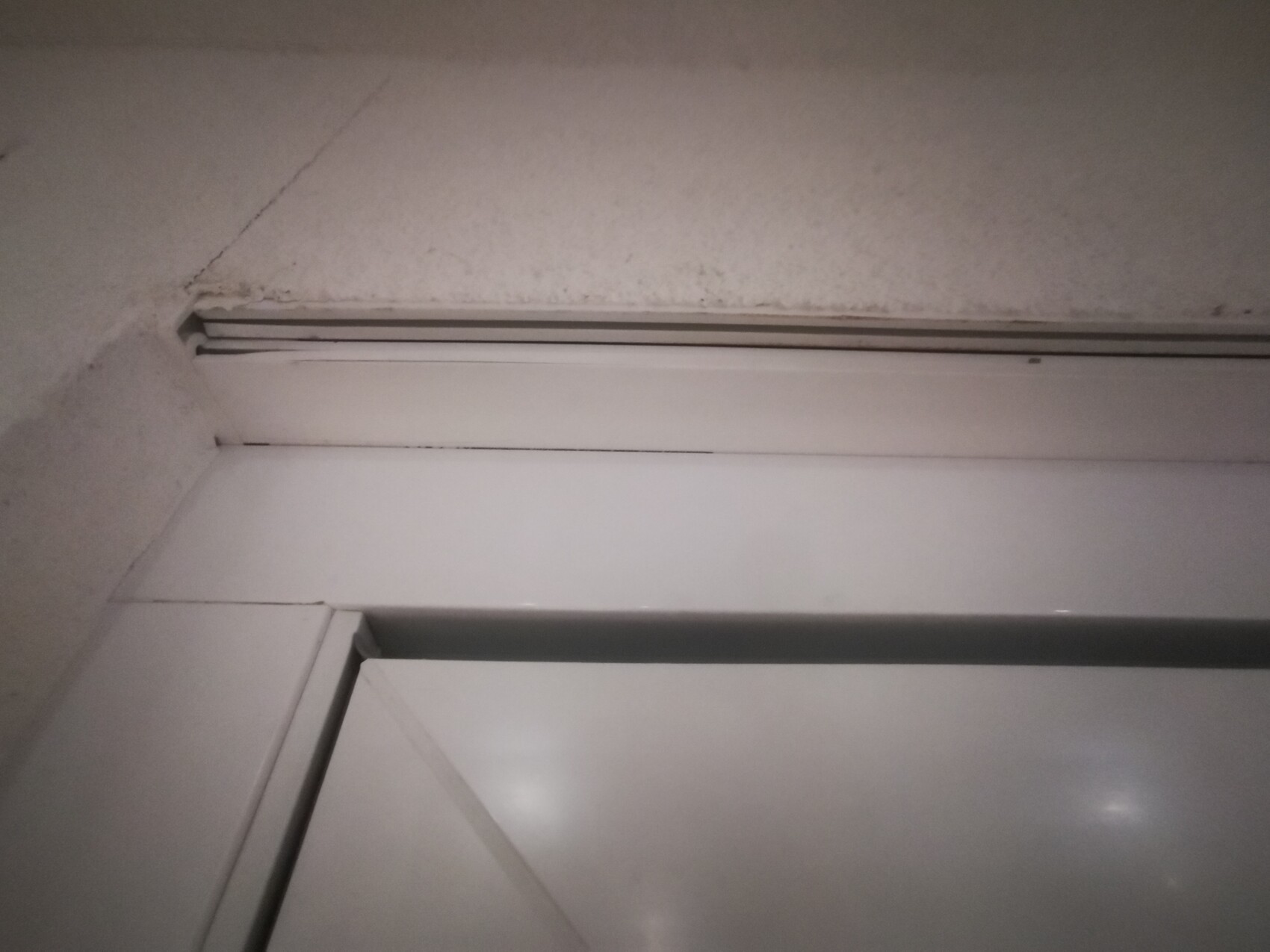Von unten aufgenommen: Metall-Türrahmen mit Glas-Schiebetür, Betonwand im Hintergrund.
