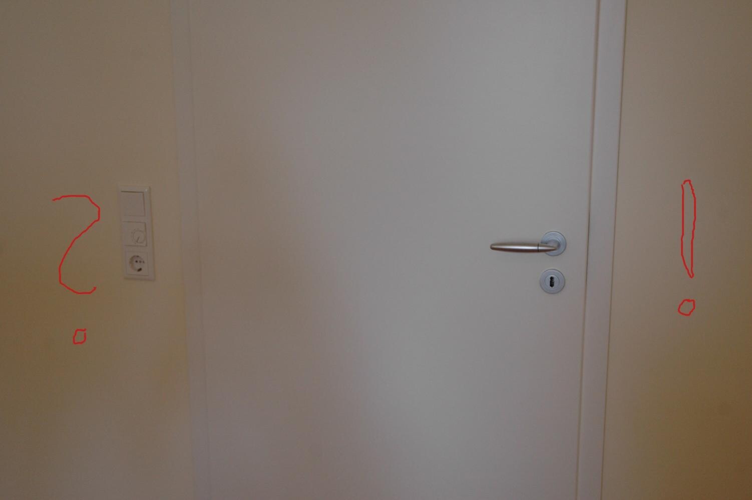 Weiße Tür mit silbernem Türgriff und daneben Lichtschalter sowie Steckdose.