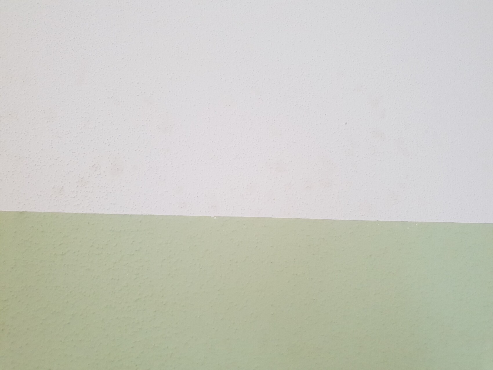 Wandoberfläche mit weißem Oberteil und hellgrüner Unterseite, diagonale Trennlinie