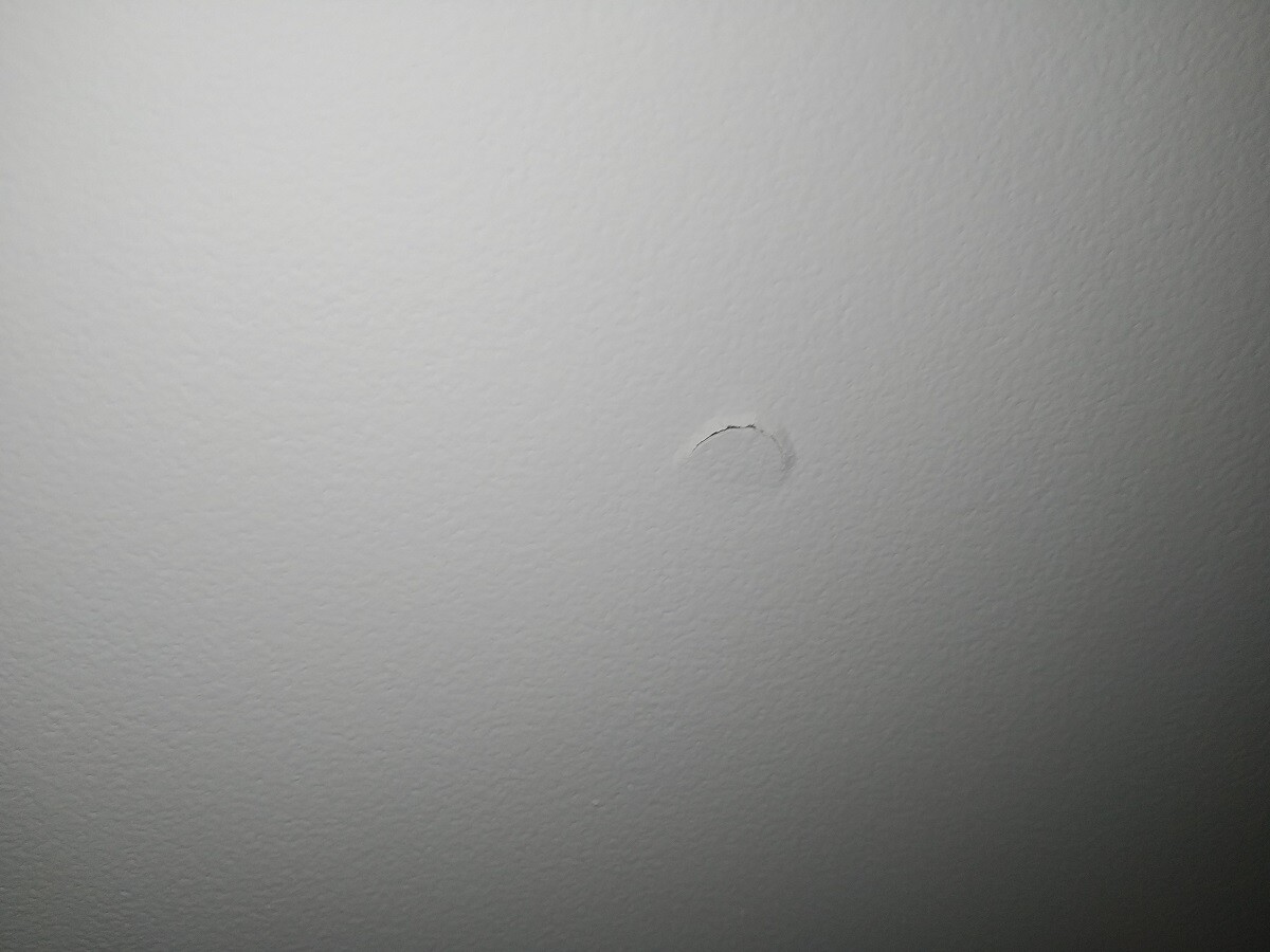 Weiße Innenwand mit kleinem runden Dellen-Schaden