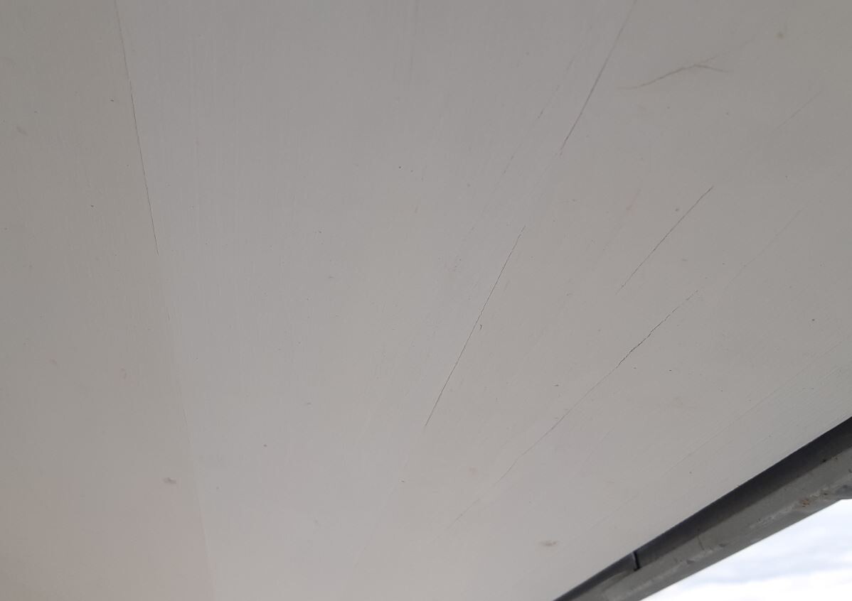 Weiße Fläche mit diagonalen Kratzspuren; unterer Rand dunkel, Himmel sichtbar.
