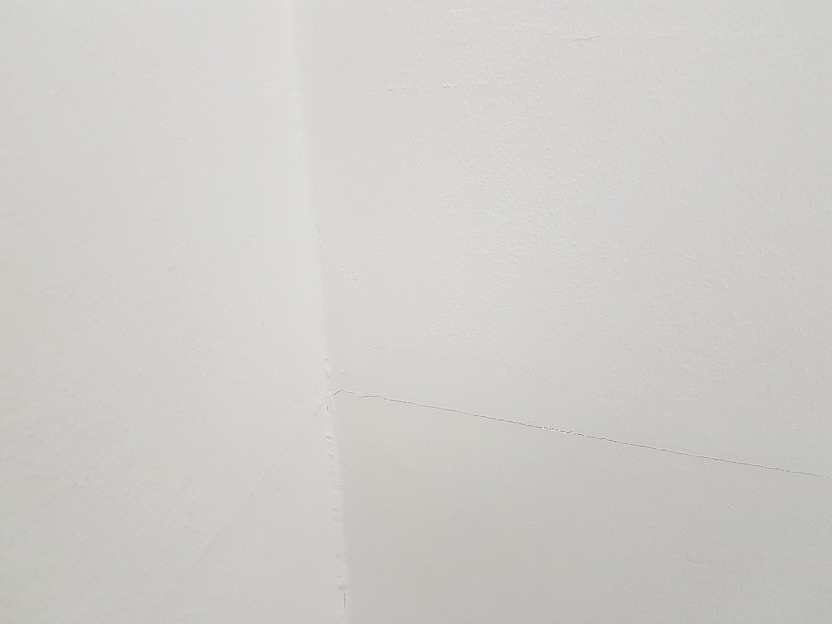 Eckige weiße Wand mit sichtbarem Riss im Eckbereich.