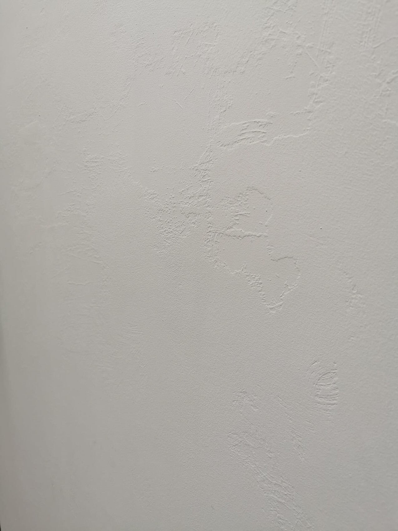 Nahaufnahme einer weißen Wand mit unregelmäßiger Putzstruktur.