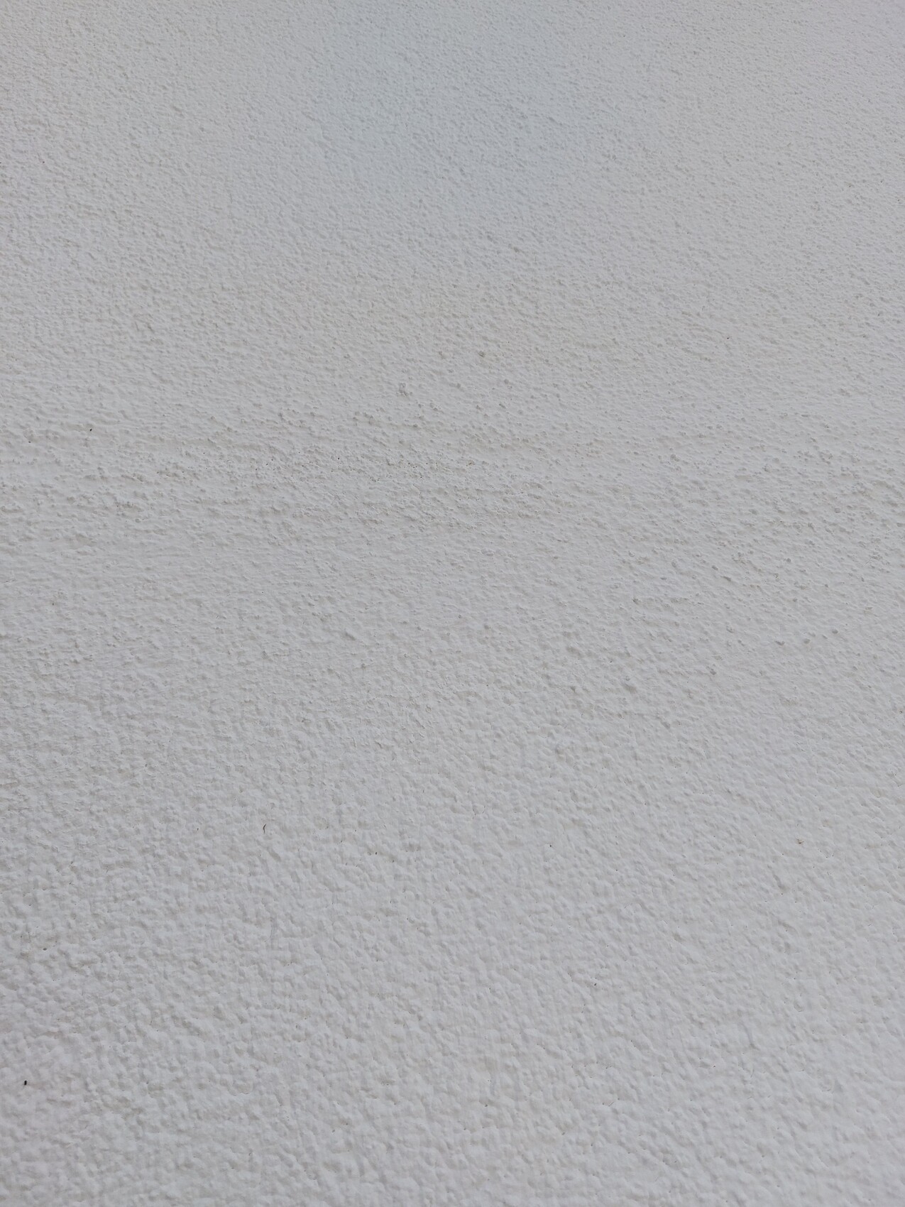 Weiße, raue Putzwand mit sichtbarer Struktur, ohne Motive