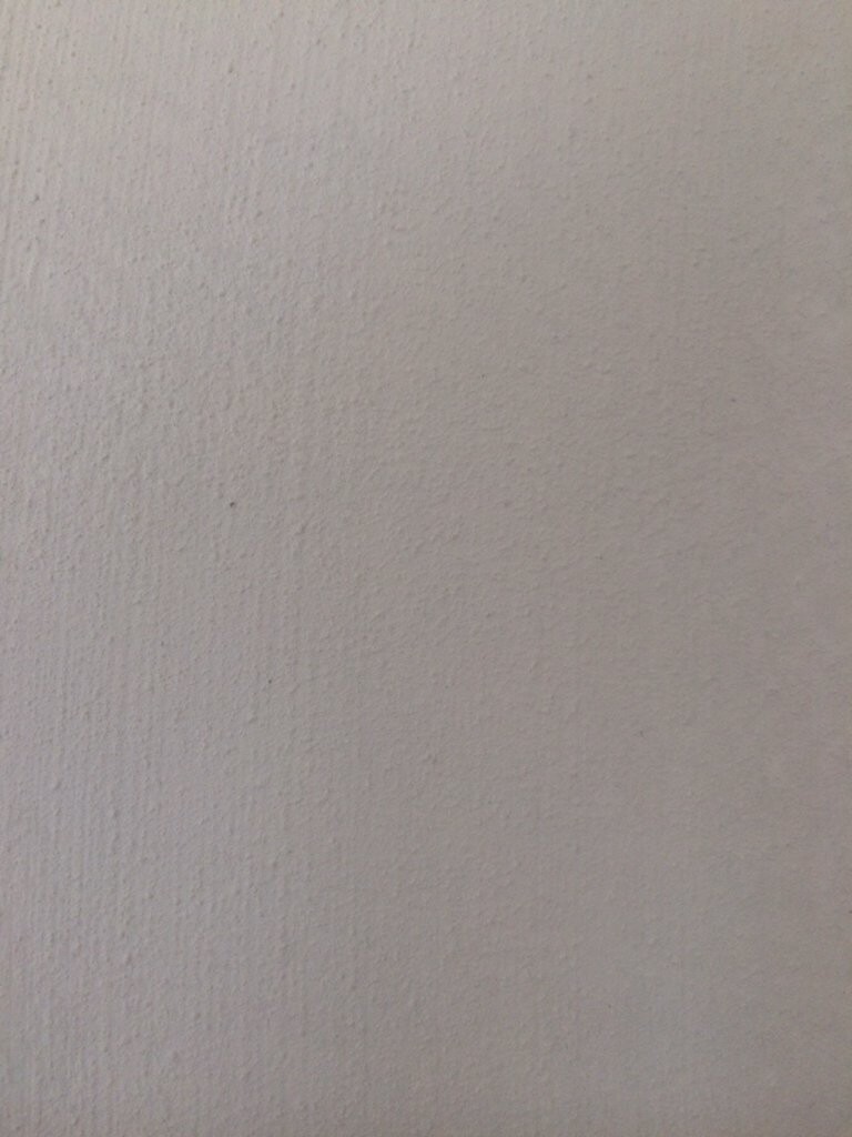 Nahaufnahme einer weißen Wand mit rauer Putzstruktur.