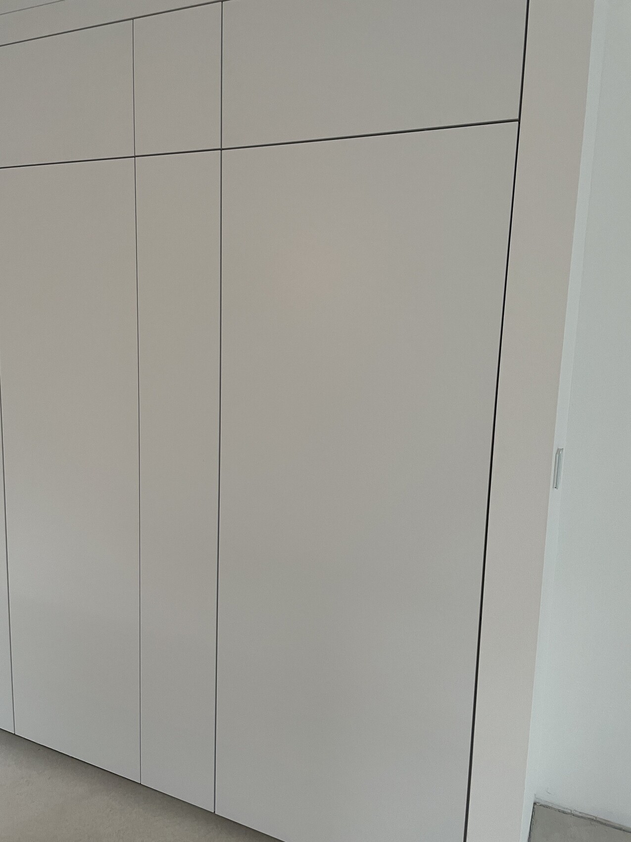 Weißer moderner Kleiderschrank mit glatten Fronten und vertikalen Fugen.