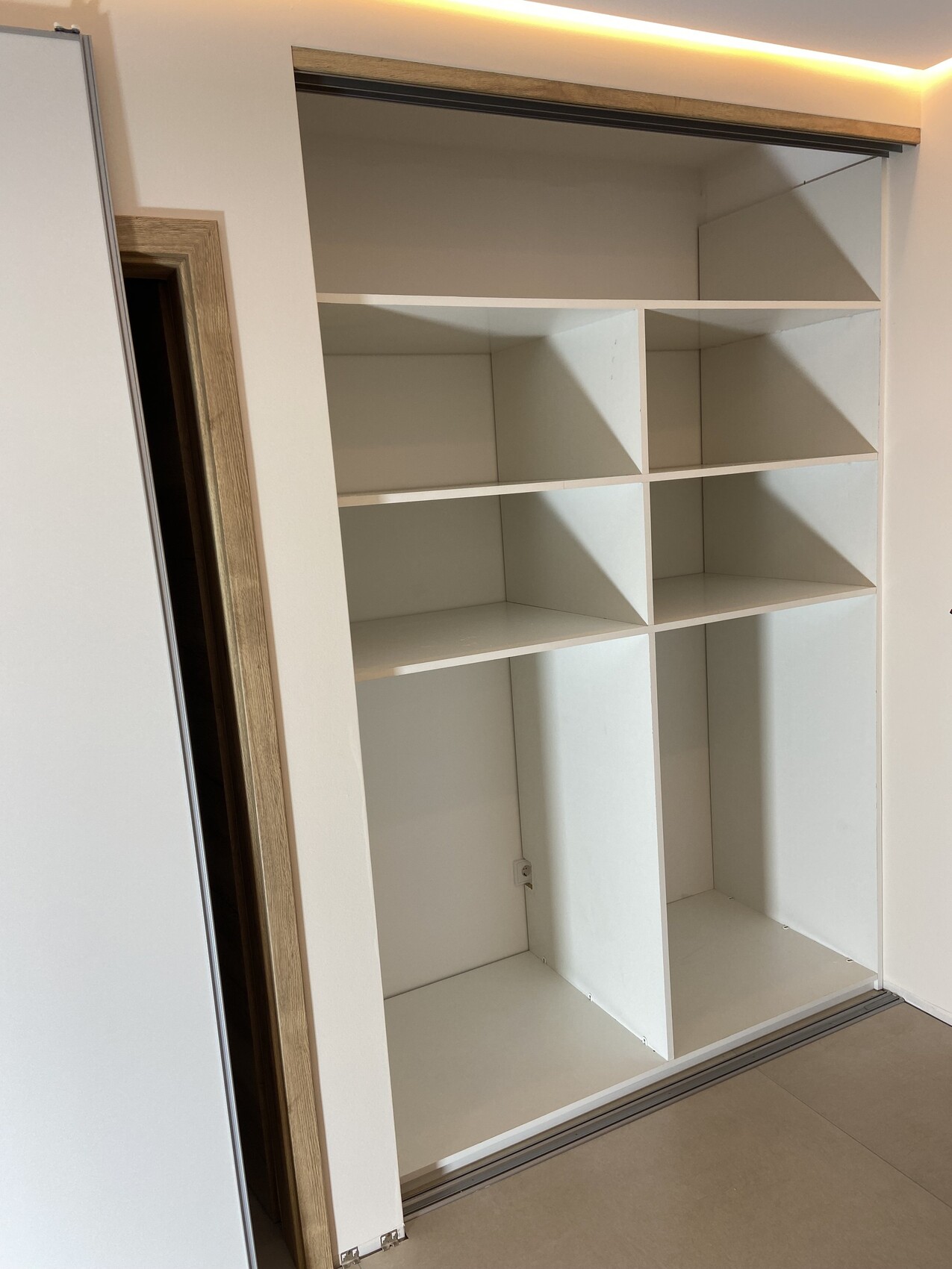 Weißer Einbauschrank mit offenen Fächern in drei Spalten und horizontalen Ablagen.