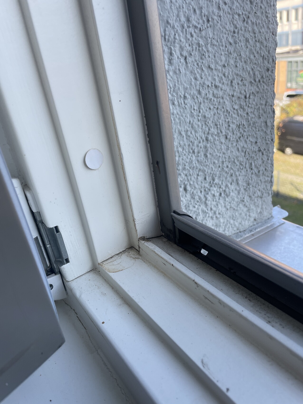 Weißer Innenfensterrahmen mit Fensterbank, daneben grob strukturierte Außenwand.