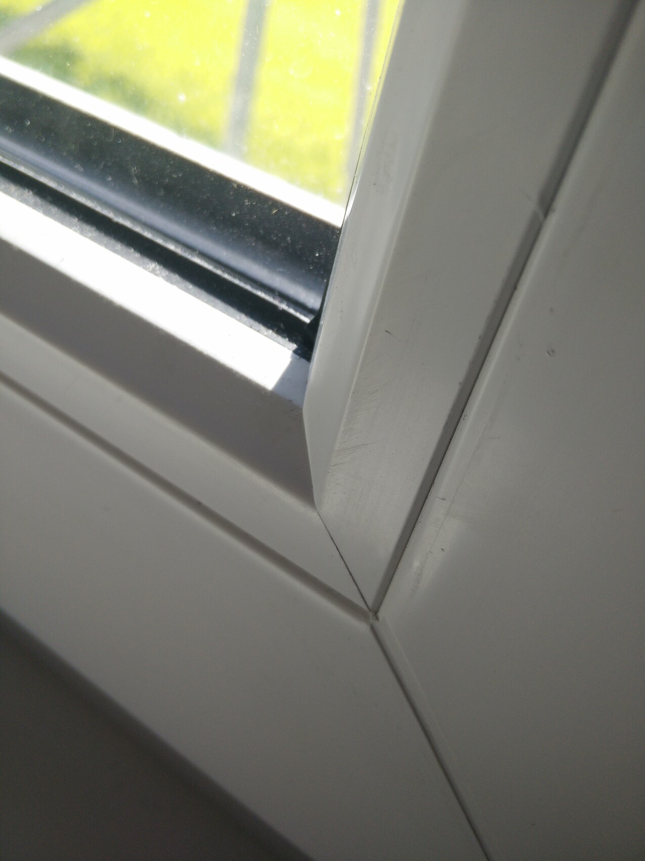 Nahaufnahme eines weißen Fensterrahmens mit Glas; Ecke der Dichtung sichtbar.