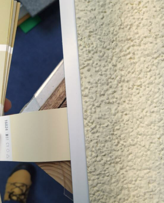 Kartenstreifen wird in den Schlitz eines weißen Rahmens geschoben; rechte Wand mit Rauputz.