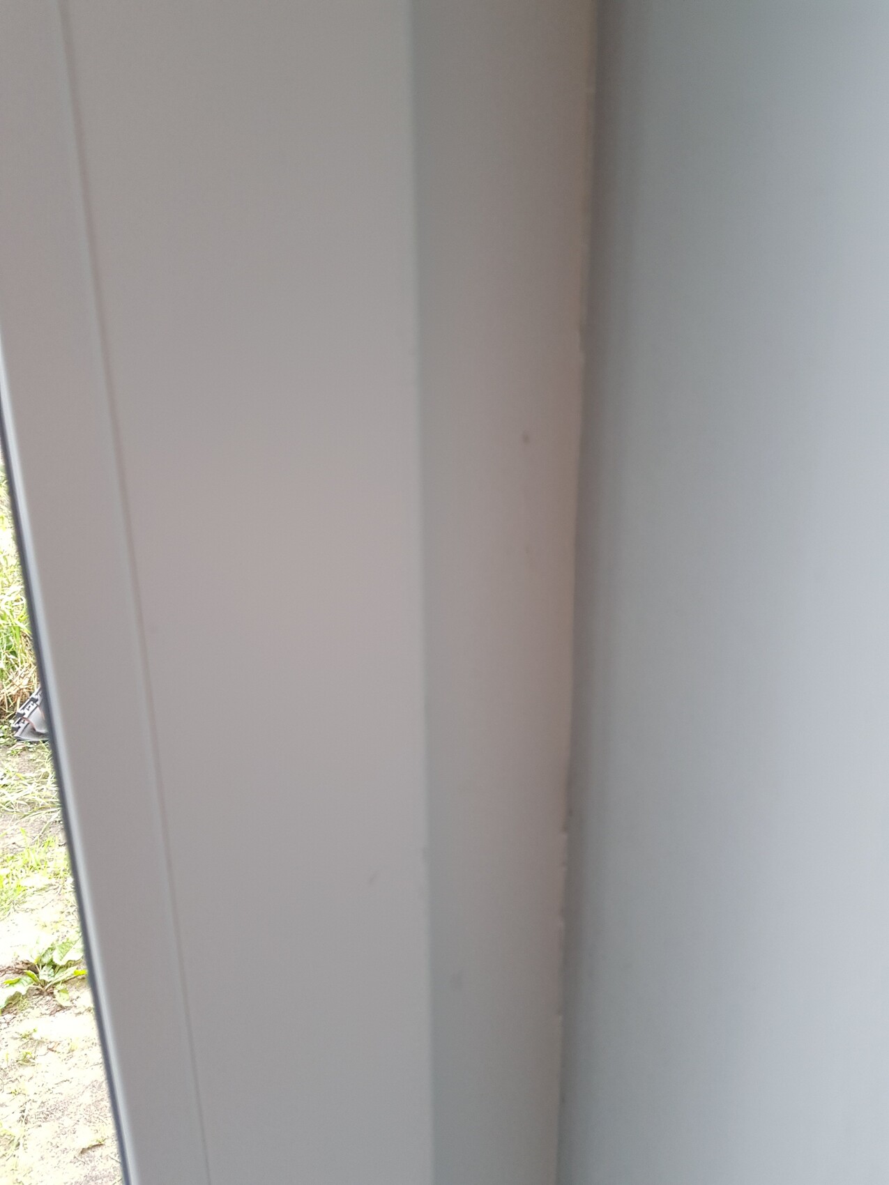Nahaufnahme eines weißen Türrahmens mit Spalt, Blick nach draußen.