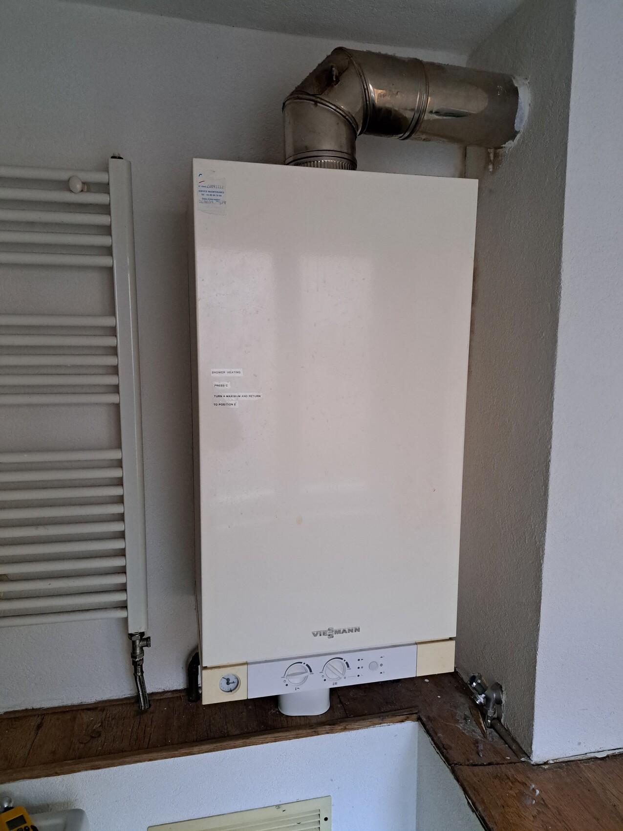 Weiße Viessmann-Heizungsanlage an der Wand mit Rohr oben, daneben Heizkörper.