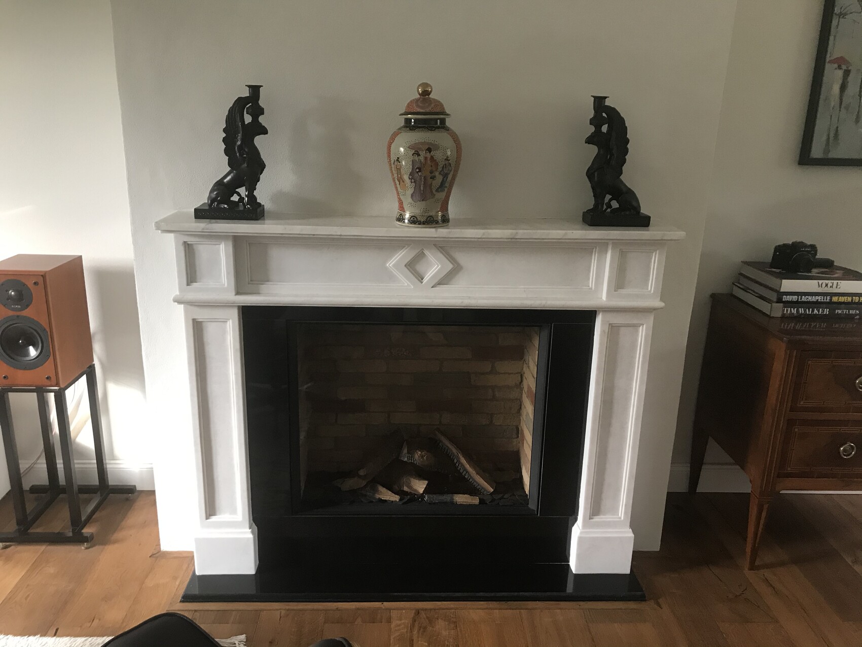 Weißer Kamin mit einer bemalten Vase in der Mitte, flankiert von zwei schwarzen Drachenstatuen.