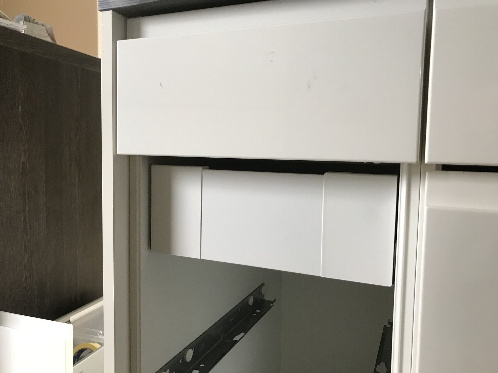 Weißer Büroschrank mit zwei Schubfächern und sichtbaren Metall-Schienen.