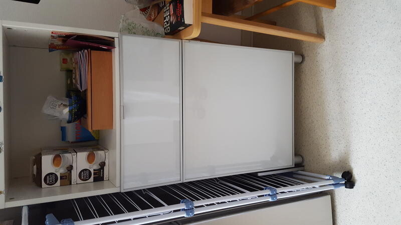 Vorratsraum mit weißem Kühlschrank, Regalen und Lagerboxen.