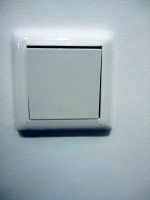 Nahaufnahme eines weißen Lichtschalters an einer Wand