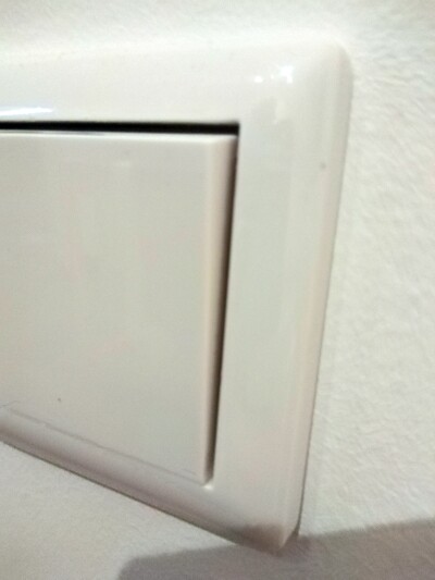 Nahaufnahme eines weißen Lichtschalters an einer hellen Wand