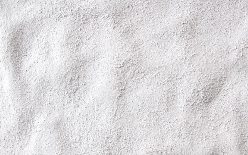 Nahaufnahme einer weißen, pudrigen Oberfläche mit unregelmäßiger Textur