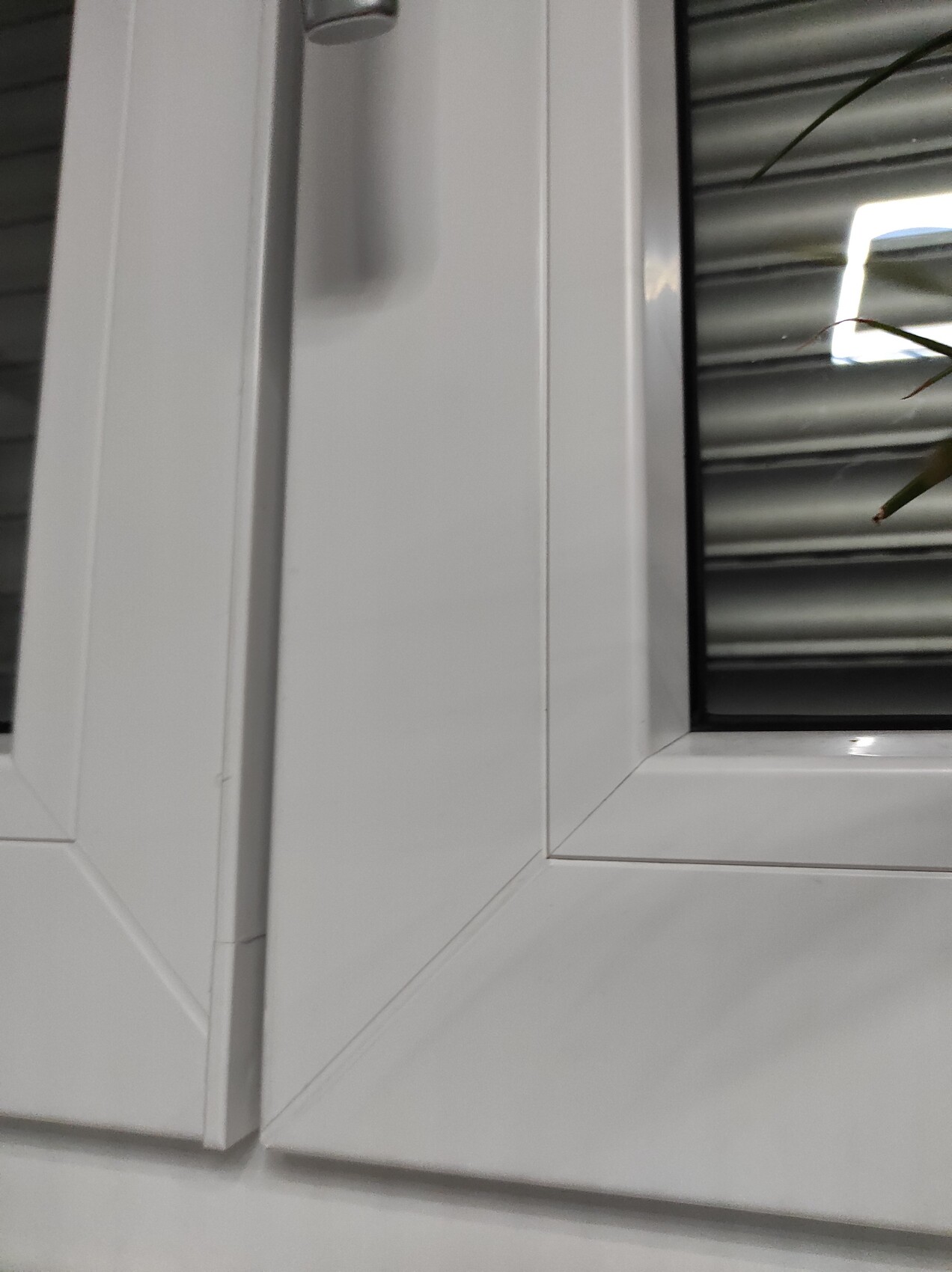 Nahaufnahme eines weißen Fensterrahmens mit Glasscheibe und hinterer Jalousie