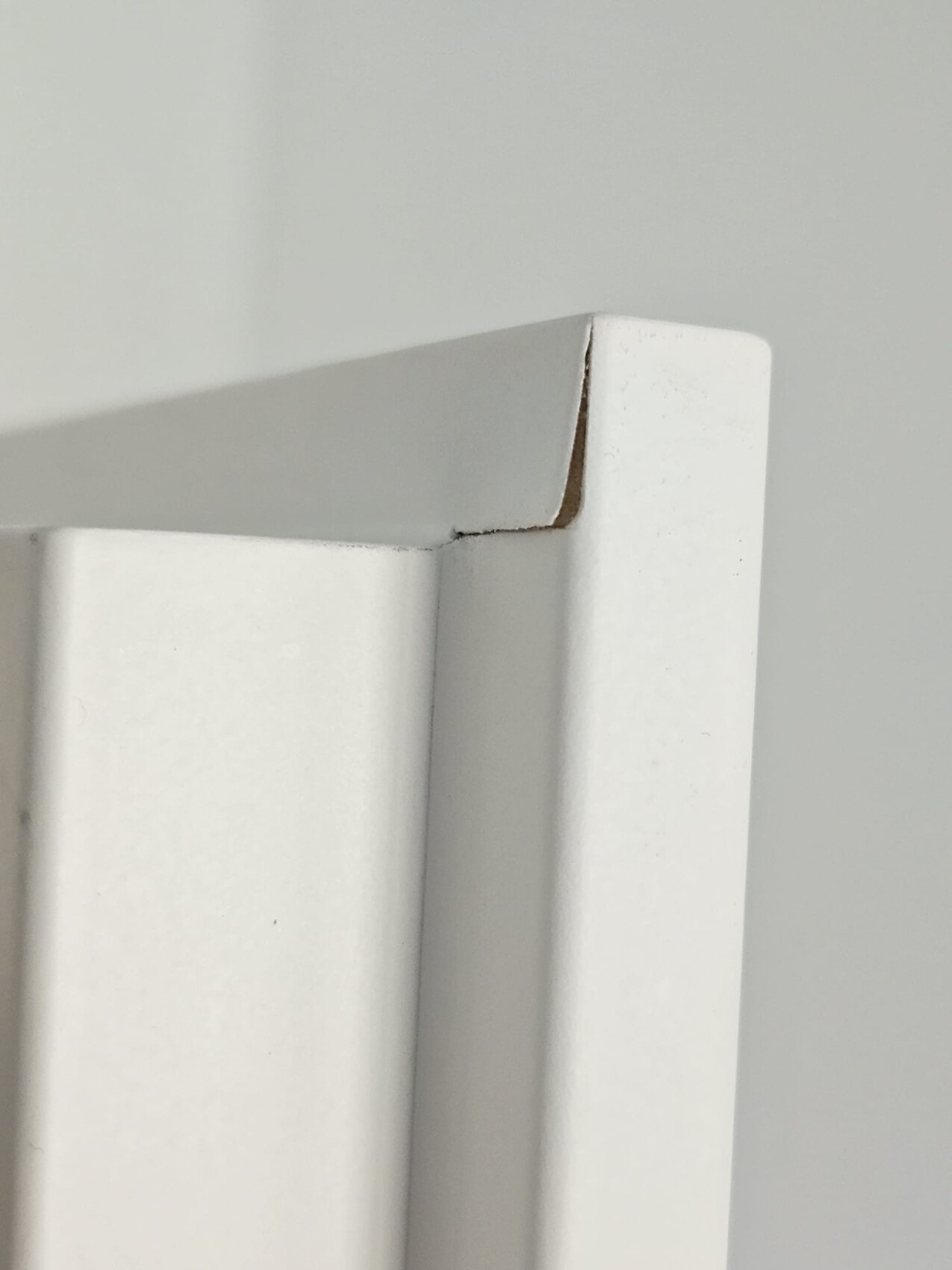 Nahaufnahme eines weißen Fenster- bzw. Türrahmenprofils mit kleinem Riss in der Ecke