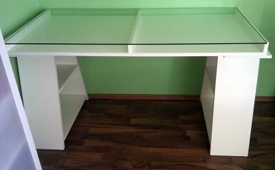 Weisser Schreibtisch mit Glastop vor gruener Wand und dunklem Holzboden