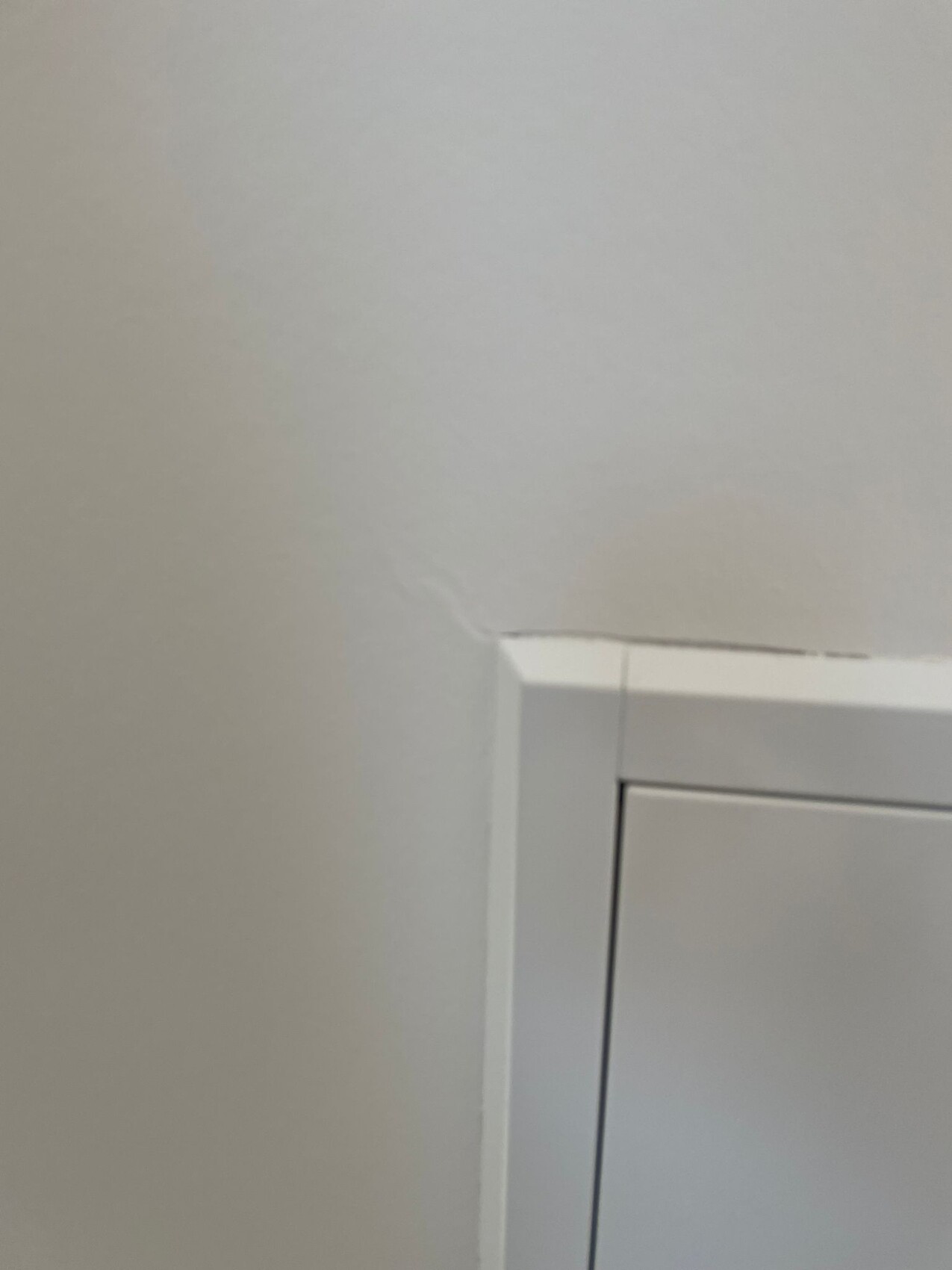 Weiße Türrahmen-Ecke an der Wand mit leichter Abplatzung am Rand