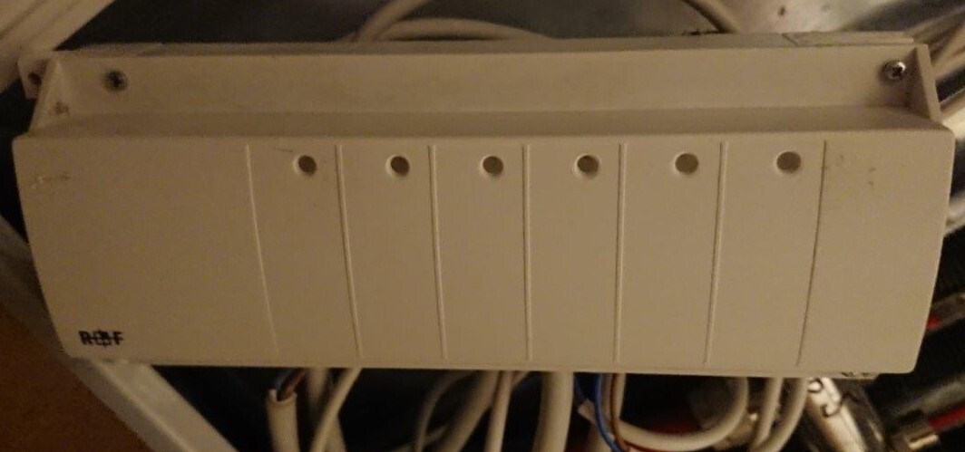 Weißer Verteilerschrank mit sieben vertikalen Fächern, darunter Kabelstränge.