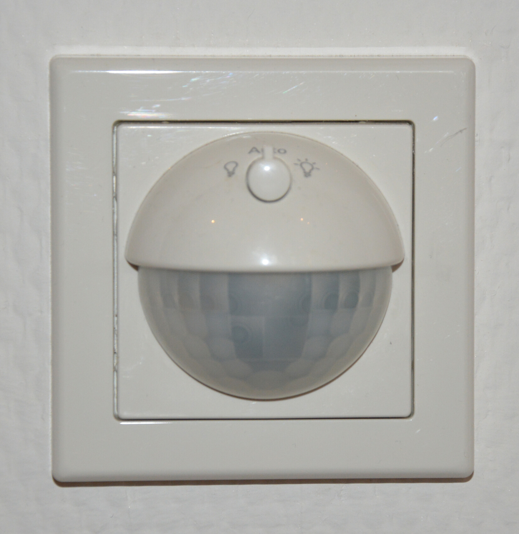 Wandsensor für automatische Beleuchtung: runde Linse hinter quadratischer Abdeckung