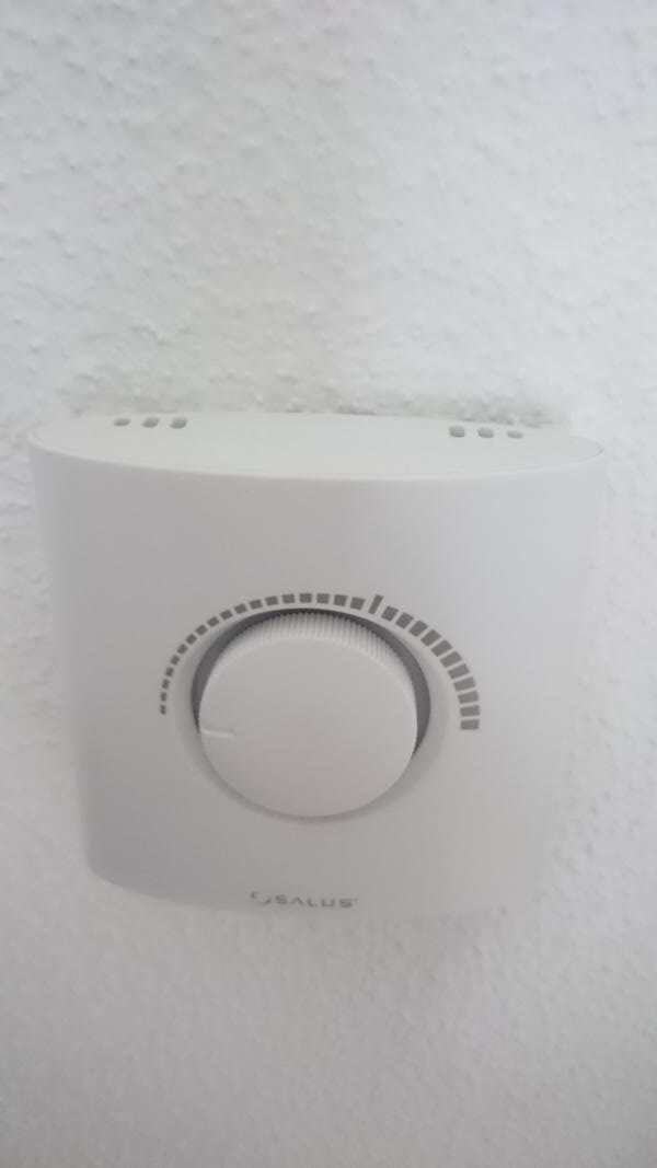 Weißer Wandthermostat mit rundem Drehknopf und Skalenmarkierungen (Salus)
