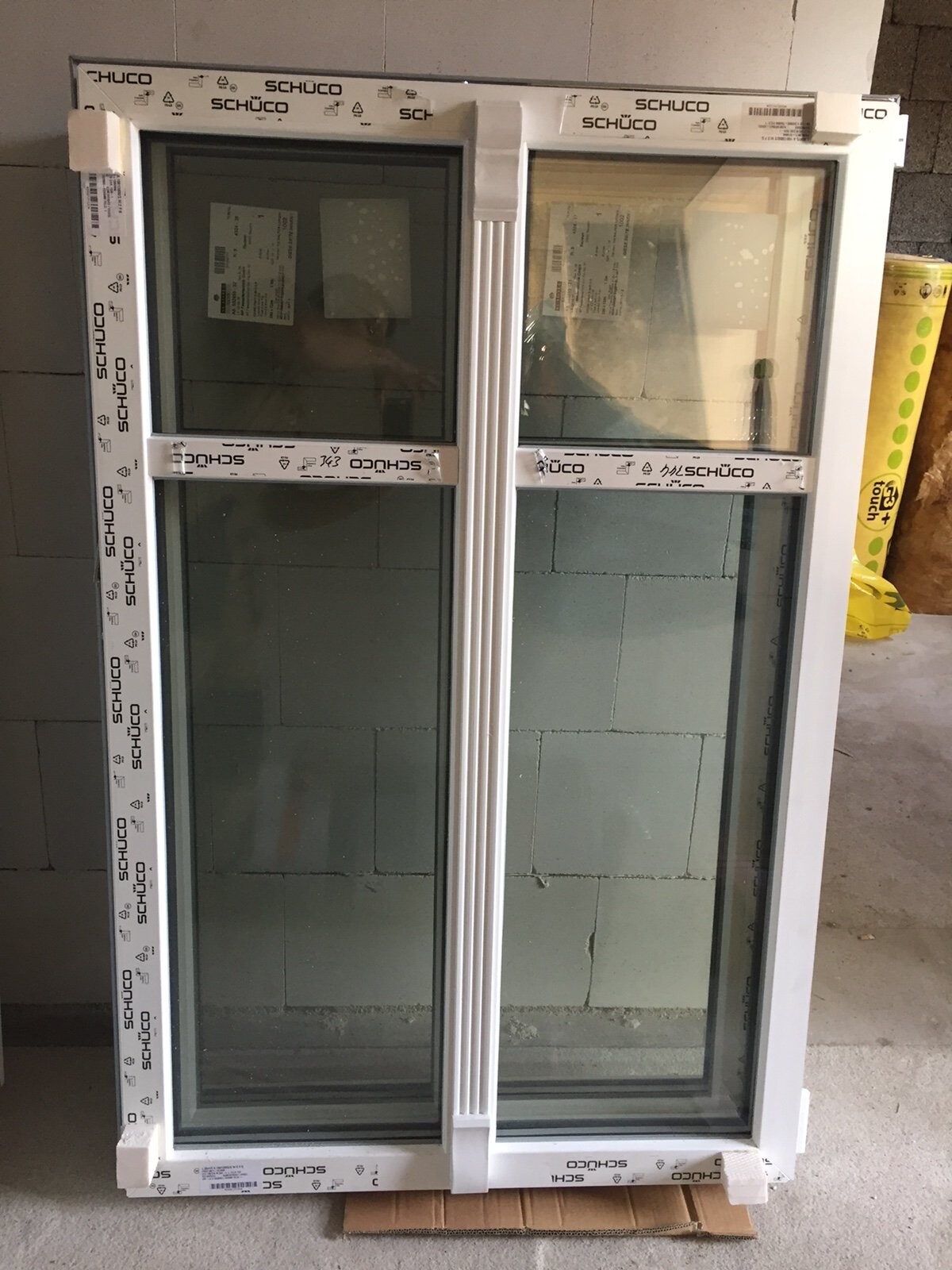 Großes weißes zweiflügeliges Fenster im Bau mit SCHUCO-Verpackung.