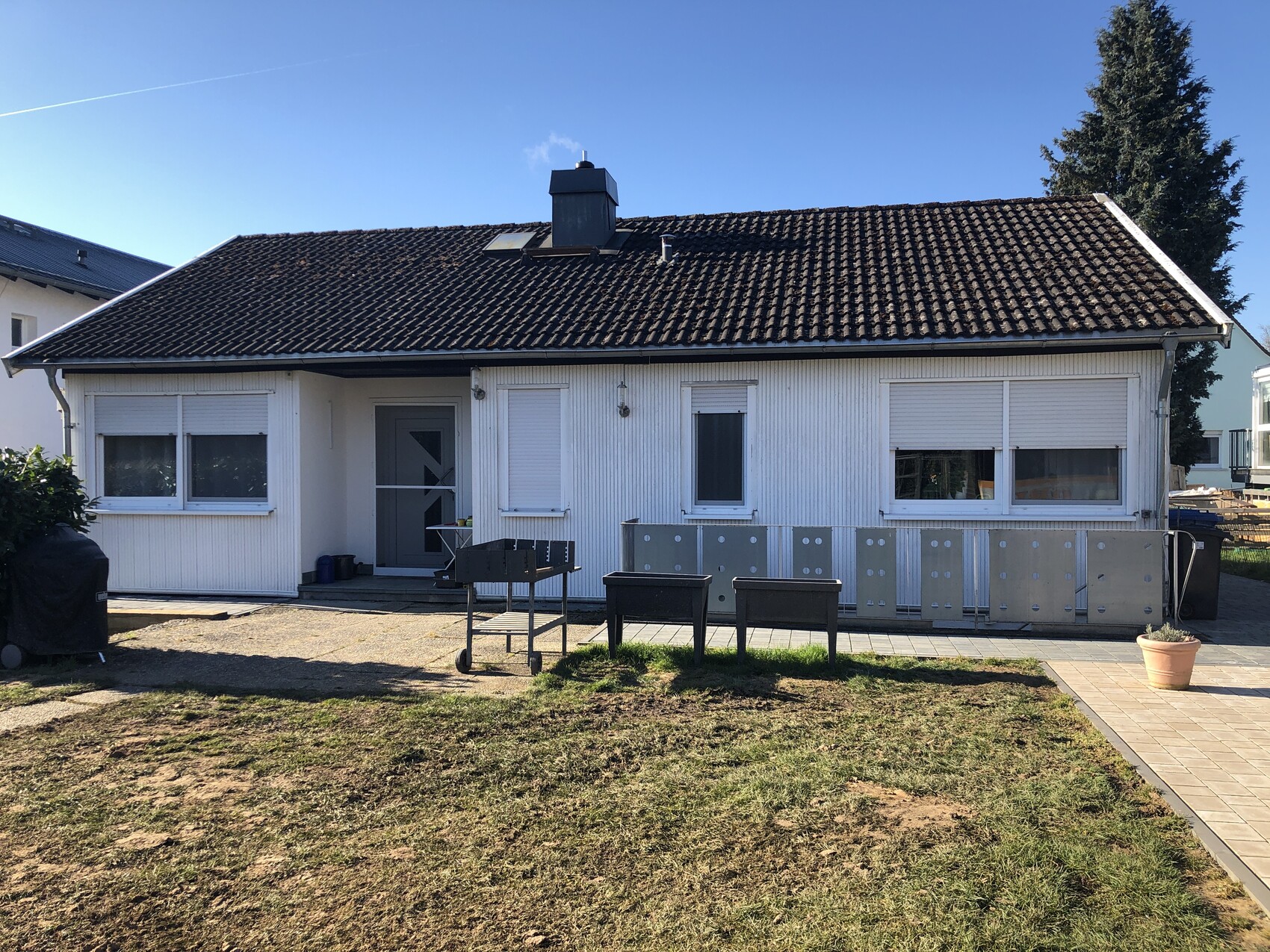 Außenansicht eines weißen Einfamilienhauses mit Dach, Terrasse und Garten