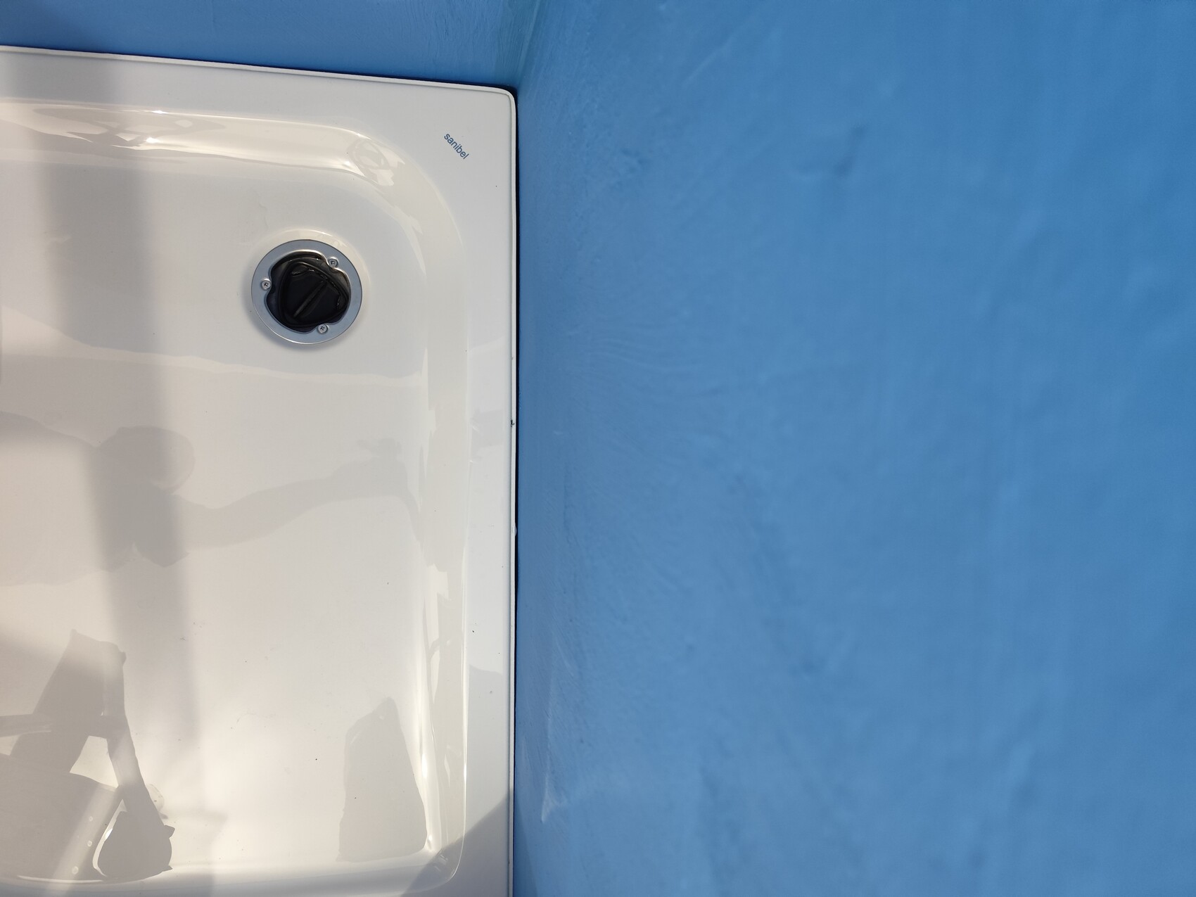 Weißes Gehäuse mit schwarzem Drehknopf vor blauer Wand.