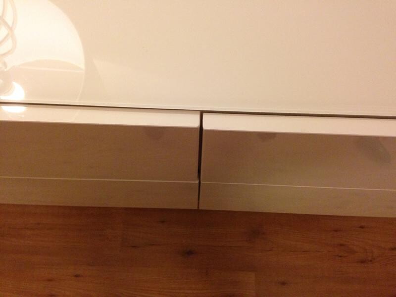 Weisses Lowboard mit zwei Schubladen steht auf Holzboden.