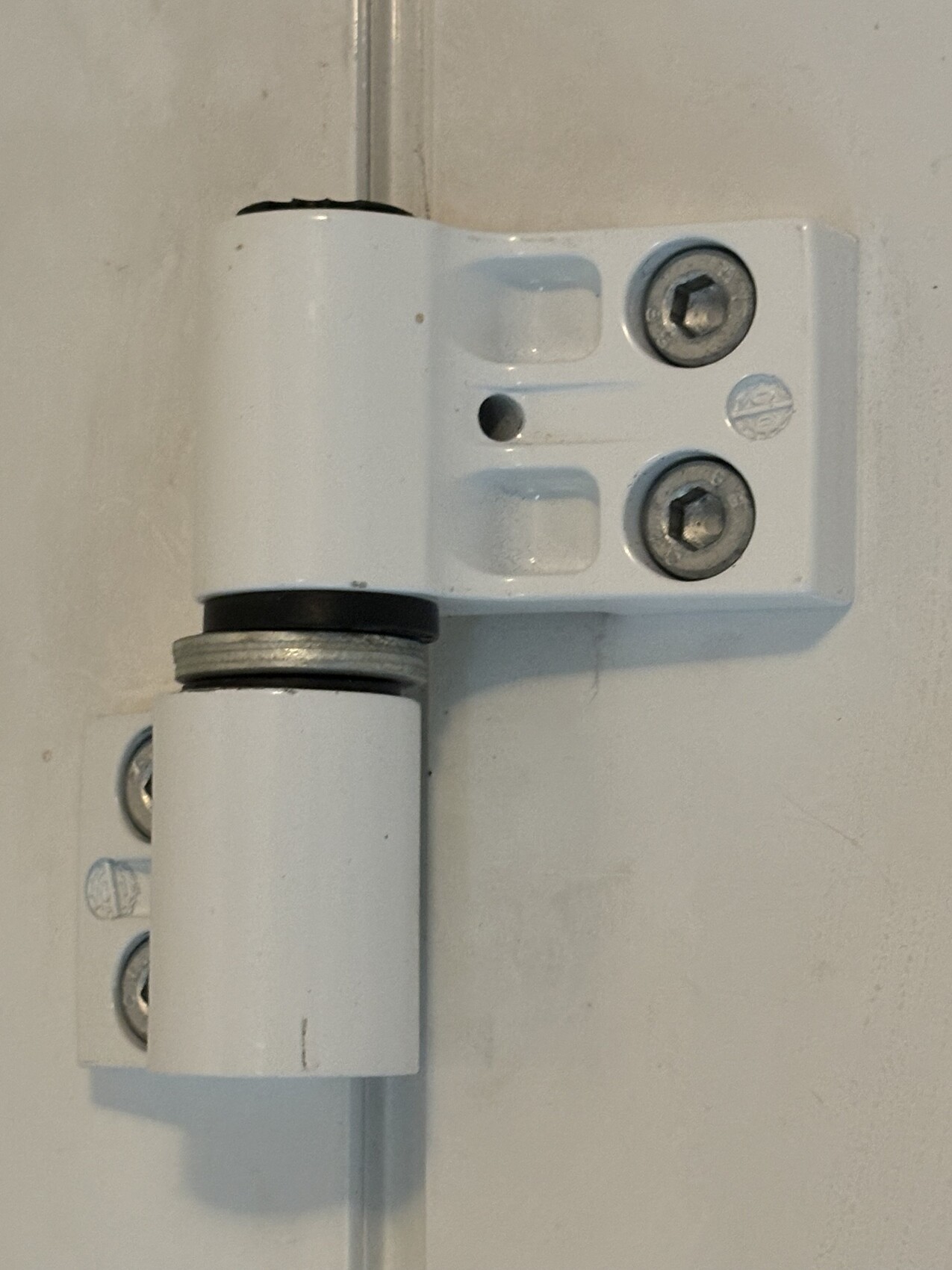 Weißes Türscharnier mit Zapfen und zwei Schrauben am Türrahmen.