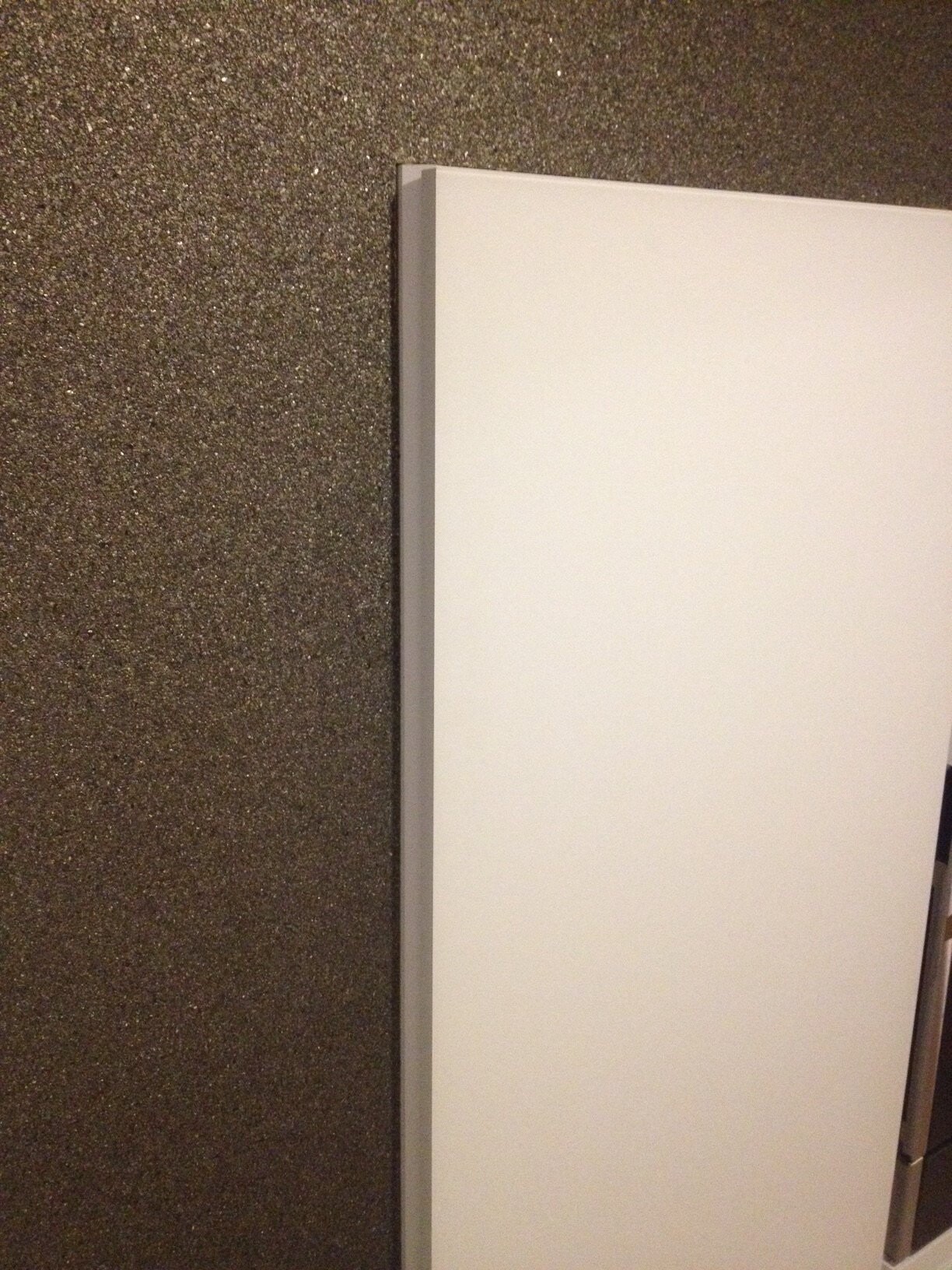 Weisses Türblatt lehnt an grob texturierter Wand, Bau- und Innenausbau-Element sichtbar
