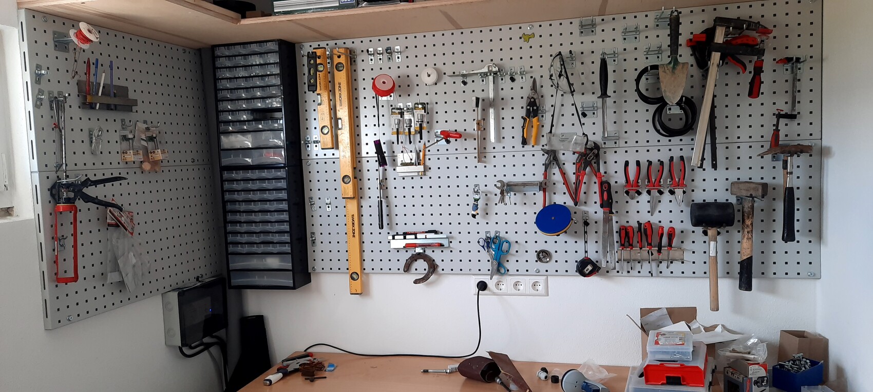 Werkstatt-Pegboard mit Werkzeugen: Hämmer, Zangen, Schraubendreher, Wasserwaagen.