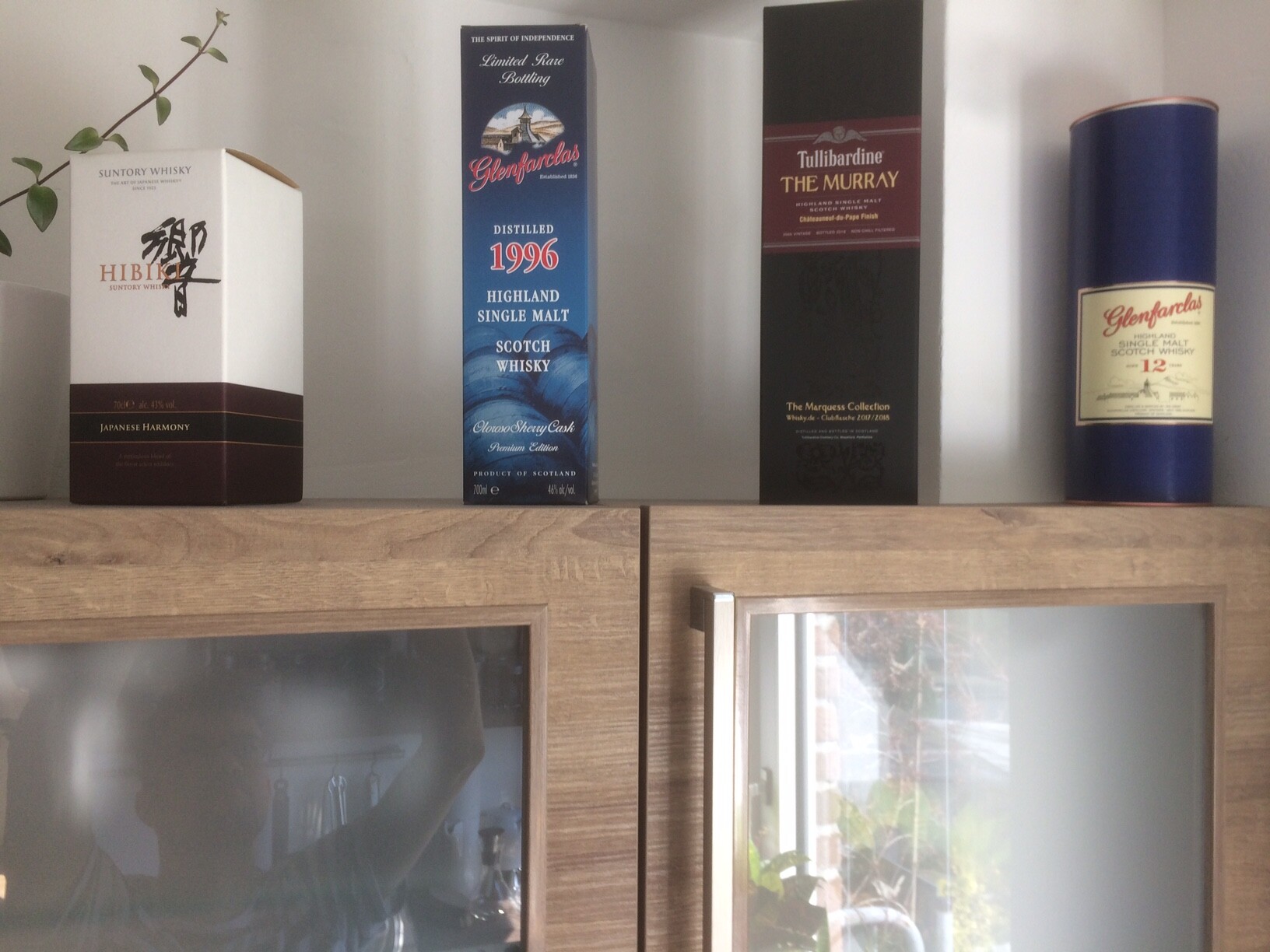 Whisky-Boxen (Hibiki, Glenfarclas 1996, The Murray) auf einem Holzregal.