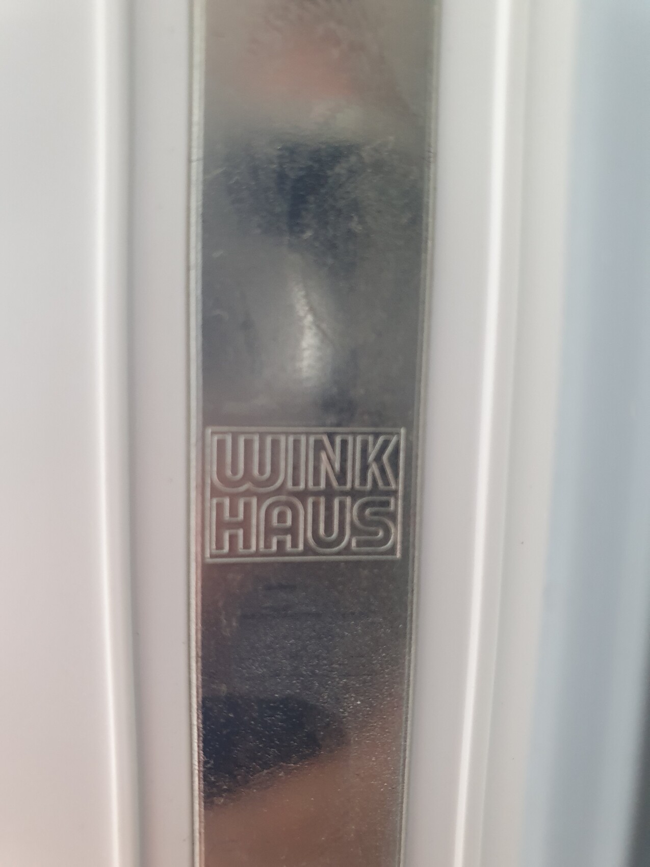 Nahaufnahme eines metallenen Türrahmenstreifens mit dem eingravierten Logo WINKI HAUS.