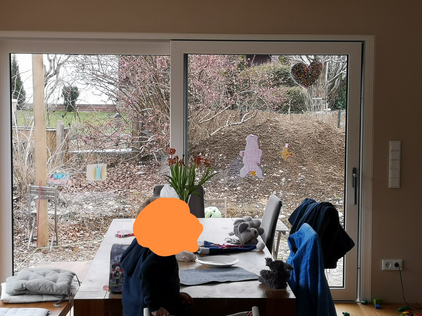Essbereich im Wohnzimmer mit Esstisch vor großen Glastüren zum Garten.