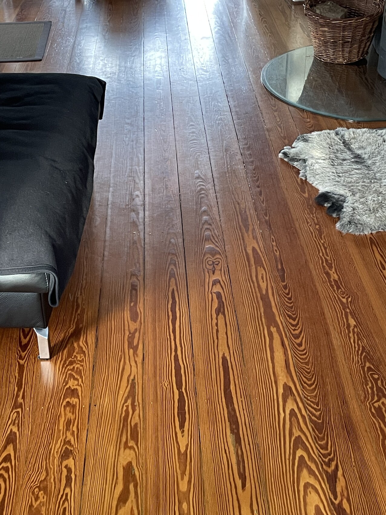 Dunkles Holzparkettboden im Wohnzimmer mit schwarzem Sofa und rundem Glastisch