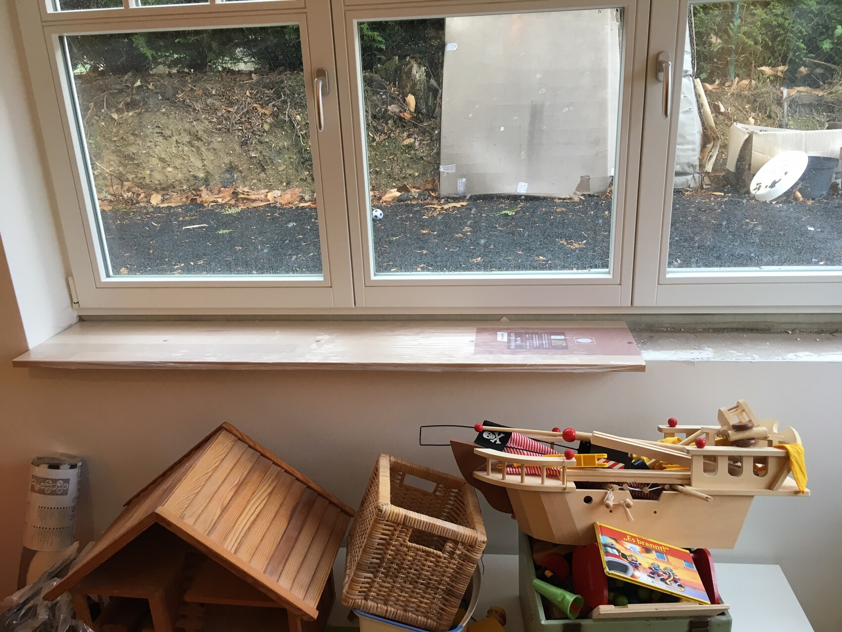 Wohnzimmer mit großem Fenster, Holzspielzeug und Spielzeugboot auf dem Boden