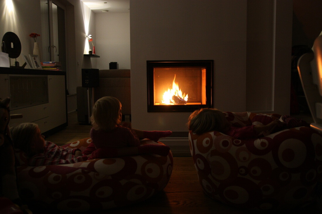 Wohnzimmer mit Kamin, gemütliche Sitzgelegenheiten und brennendem Feuer