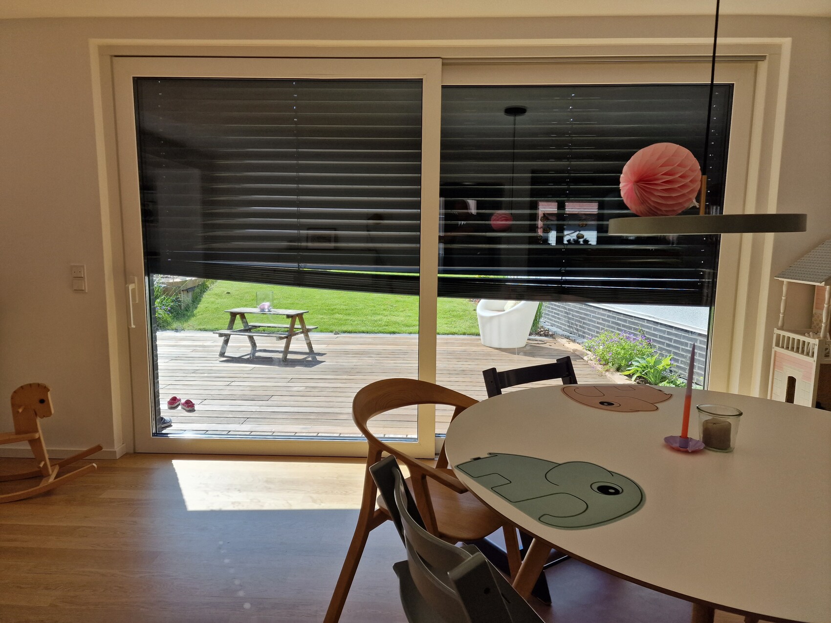 Runder Tisch mit Elefanten-Design, pinkem Papierlampion; Blick auf Terrasse mit Holztisch draußen