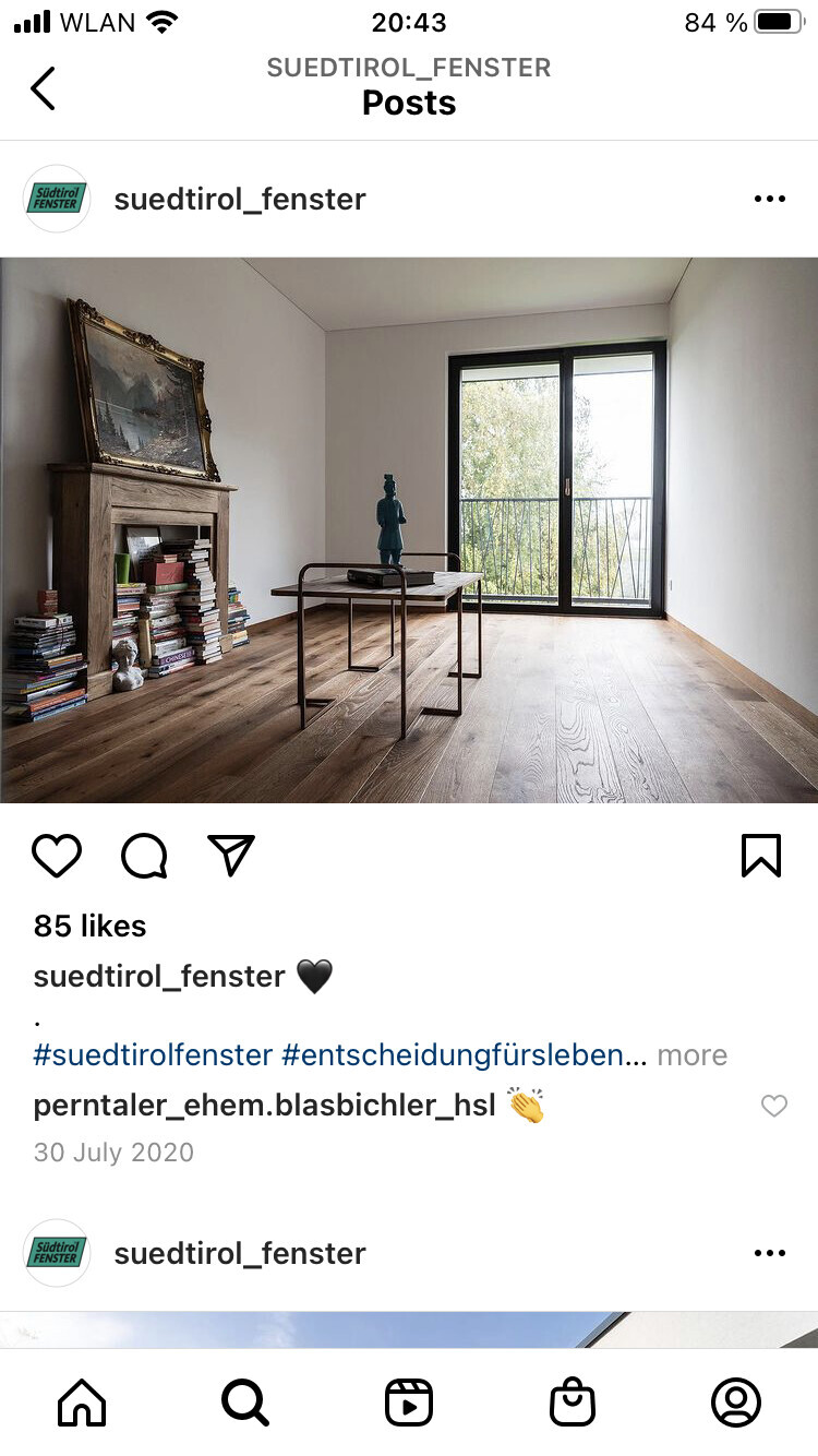 Modernes Wohnzimmer: Holzboden, Kamin, Bücherstapel, Tisch mit Skulptur, Glasfront zum Balkon.