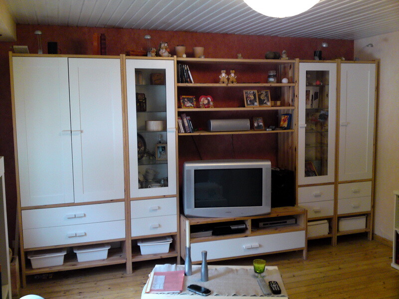 Wohnzimmer mit weißen Schränken, Fernseher und Holzregal auf Holzboden