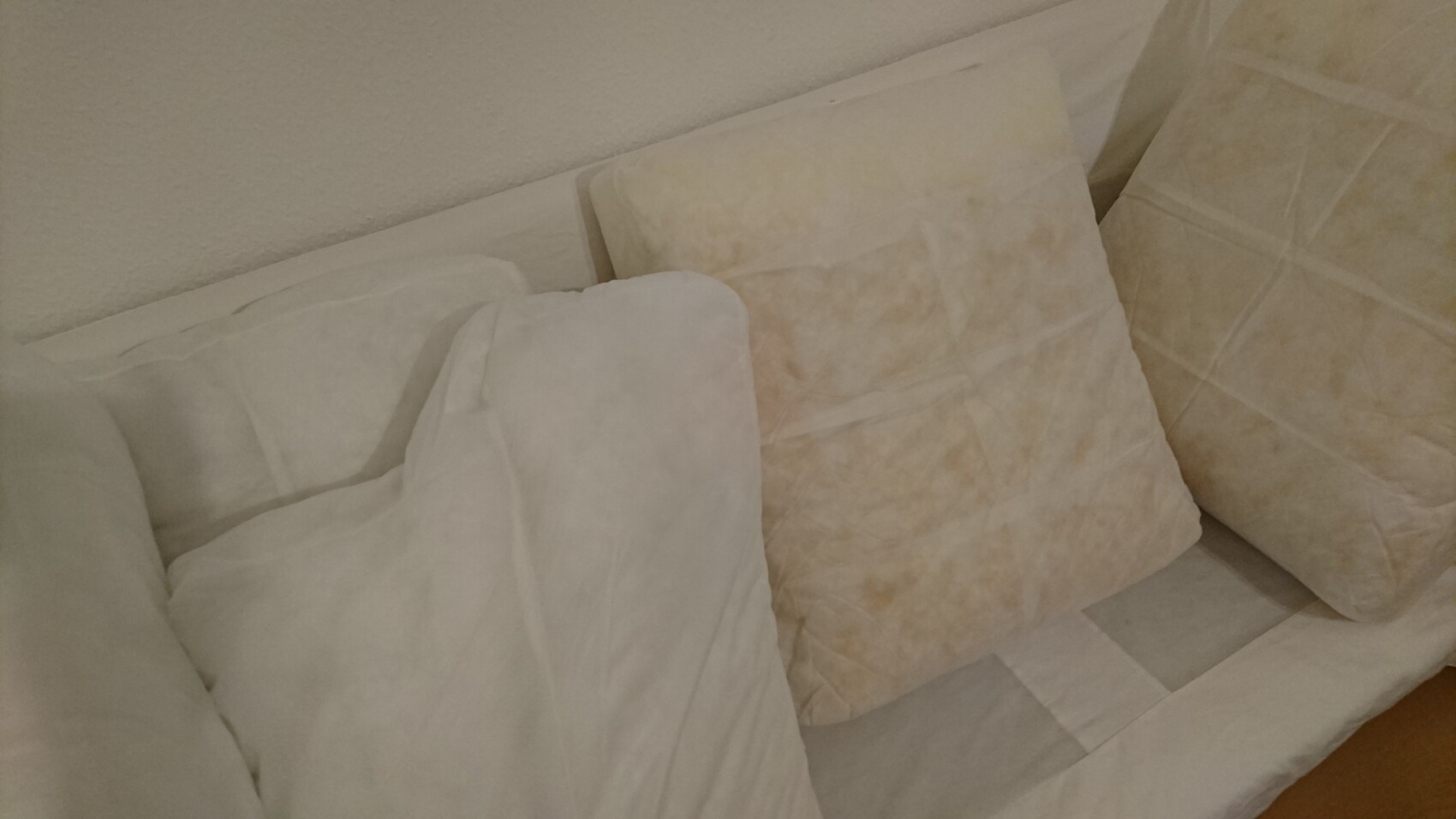 Helles Wohnzimmer mit cremefarbenem Sofa und Kissen auf Fliesenboden