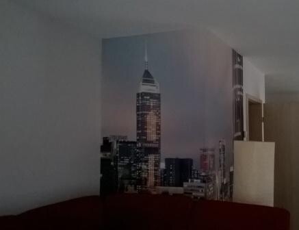 Wohnzimmer mit großem Stadt-Skyline-Wandbild hinter Sofa und Regal