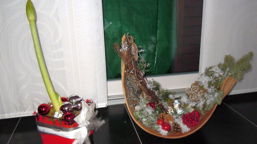 Gemütliches Wohnzimmer mit Weihnachtdeko: Holzschale, Tannenzweige und Kugeln am Fenster.