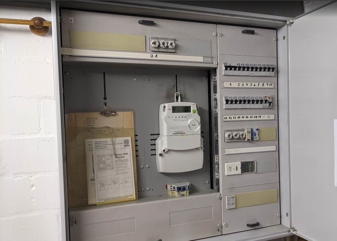 Elektrischer Zähler und Verteilerkasten mit Sicherungen in einem Wandgehäuse.