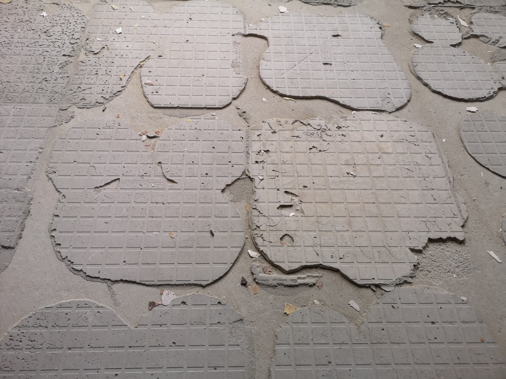 Zerbrochene Terrassenplatten aus Beton auf Sanduntergrund